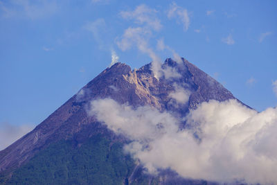 Low angle view of volcanic mountain against cloudy sky