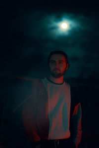 Portrait of boy standing against illuminated moon