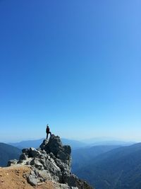 Man standing on mountain peak against clear blue sky