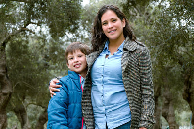 Portrait of happy mother and daughter against trees