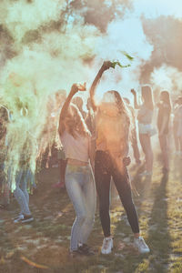 Happy friends playing with powder paint while standing outdoors