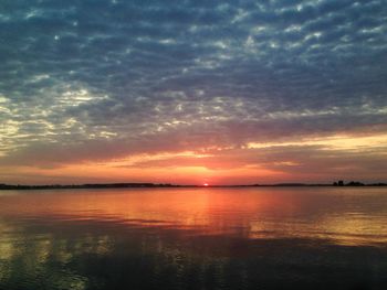 Scenic view of sea against cloudy sky at sunset