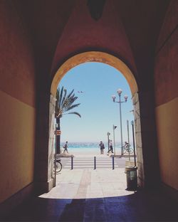 Tourists at the beach seen through archway