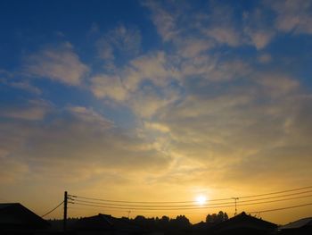 Low angle view of silhouette electricity pylon against sky during sunset