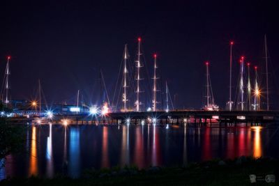 Illuminated harbor by river against sky at night
