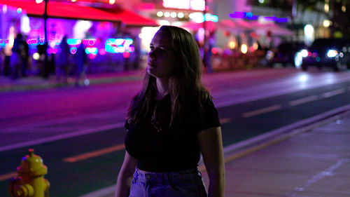 Rear view of woman walking on street at night