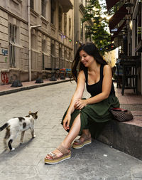 Young woman with dog sitting in city