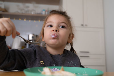 Cute girl eating food at home