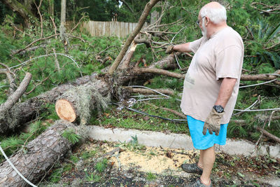 Full length of man standing on log in forest