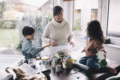 Happy woman separating waste with son and daughter at home