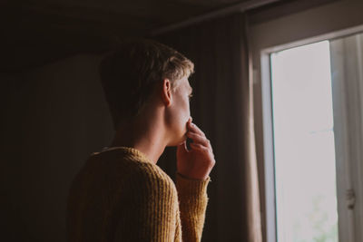 Portrait of man looking through window at home