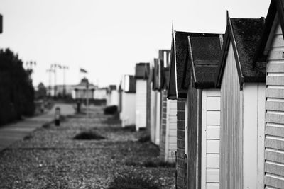 Beach huts by walkway against clear sky