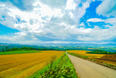 Road amidst field against sky