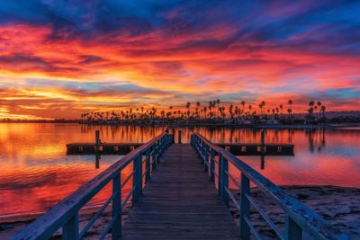 Pier over sea against orange sky