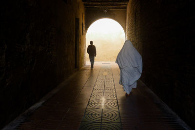 Rear view of man walking in tunnel