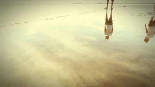 Low section of reflection on beach against sky