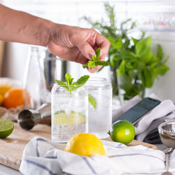 Mixologist making hard seltzer cocktail while watching instructional video on phone at home