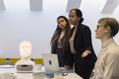 Business people discussing robot voice assistant during meeting