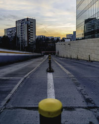 Road by city against sky during sunset