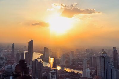 Modern buildings in city against sky during sunset