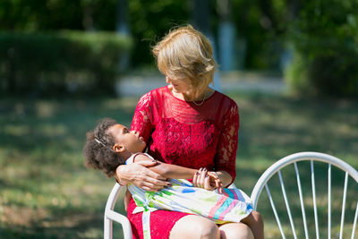 Blond woman looking at daughter while sitting on chair