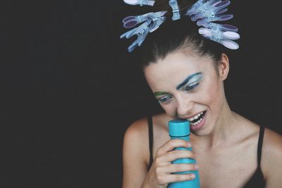 Young woman with blue bottle against black background