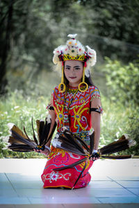 Portrait of smiling young woman standing against trees