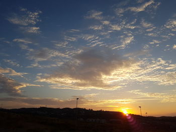 Silhouette trees against dramatic sky during sunset