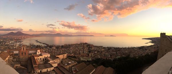 High angle view of townscape by sea against sky during sunset