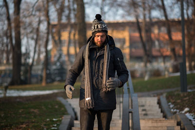 Young man in warm clothing moving down on steps at park