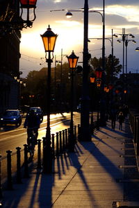 Street lights on footpath in city at sunset