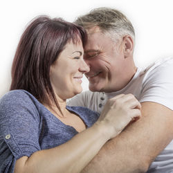 Close-up of happy couple sitting against white background