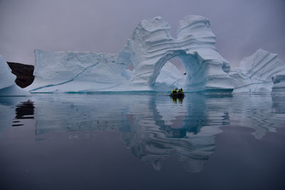 Scenic view of natural arch, icebergs and mirror like bay in eastern greenland