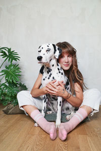 Portrait of woman with dog sitting on floor at home