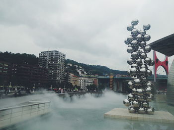 City at waterfront against cloudy sky