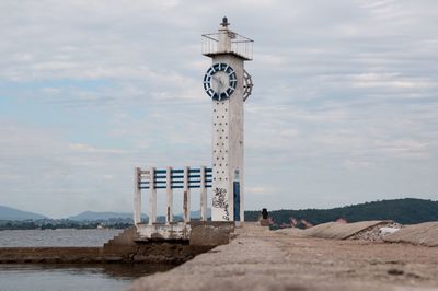 Lighthouse by sea against sky