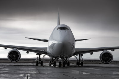 Airplane on airport runway against sky