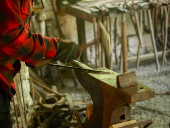 Midsection of man working at metal workshop