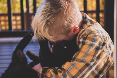 Side view of boy holding camera while looking through window