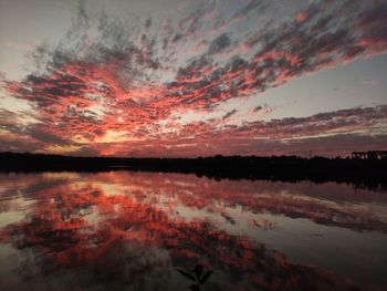 Scenic view of lake against dramatic sky during sunset