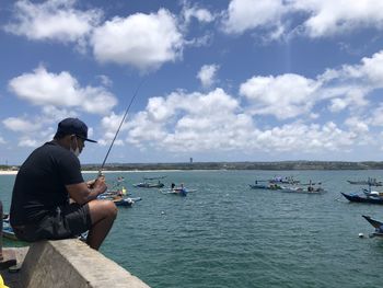 Man fishing in sea against sky