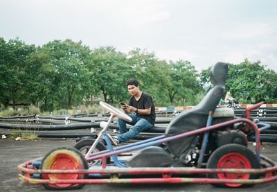 Portrait of man sitting by sports car on sports track