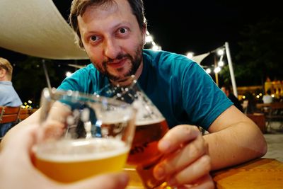 Midsection of man holding drink sitting on table