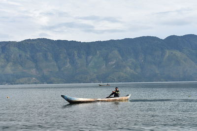 Fisherman fishing in sea against mountain