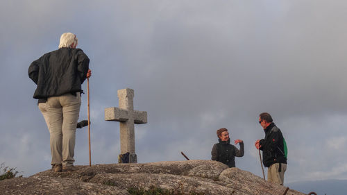 Rear view of people standing on rock against sky