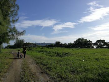 Rear view of men walking on field against sky