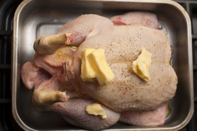 High angle view of raw chicken with butter on roasting pan