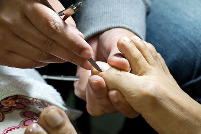 Cropped hands of woman cleaning customer toenails at spa