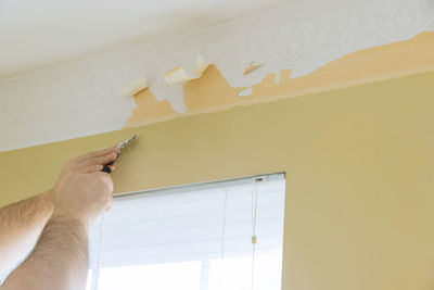 Low angle view of man working on wall at home