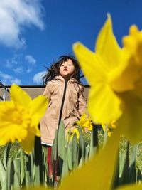 Portrait of girl jumping between yellow flower